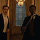 Harris Dickinson and Djimon Hounsou in suits with weapons.